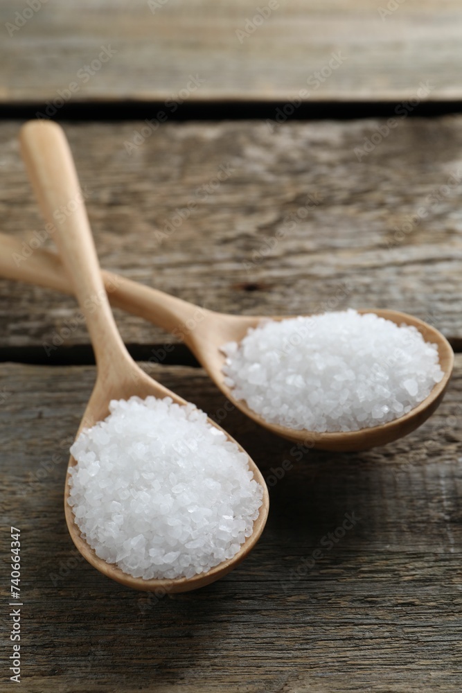 Organic salt in spoons on wooden table, closeup Organic salt in spoons on wooden table, closeup