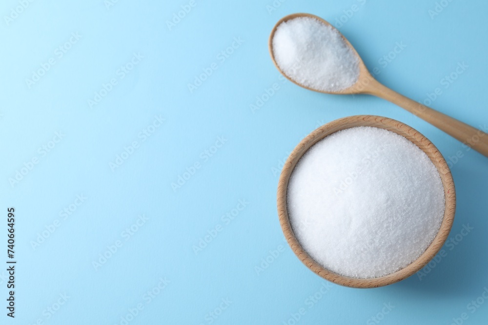 Organic white salt in bowl and spoon on light blue background, top view. Space for text Organic white salt in bowl and spoon on light blue background, top view. Space for text