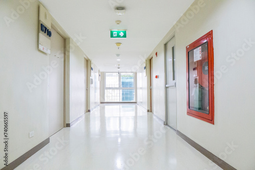 Modern and clean hospital corridor with smoke detector, fire exit sign and fire hose reel cabinet