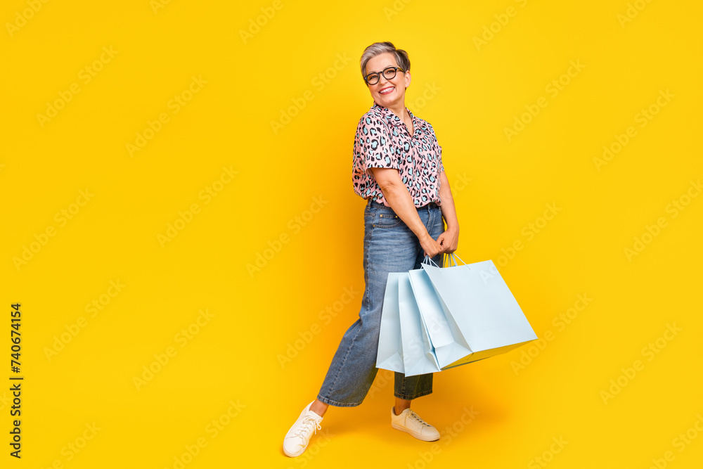 Full size photo of pretty retired female shopping bags big sales dressed stylish leopard print outfit isolated on yellow color background Full size photo of pretty retired female shopping bags big sales dressed stylish leopard print outfit isolated on yellow color background
