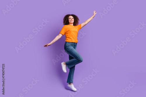 Photo of joyful cheerful woman wear orange clothes jump up fly air travel isolated on purple color background