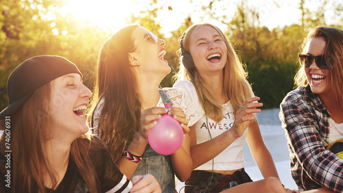 Portrait of best friends laughing together while blowing up balloons photo