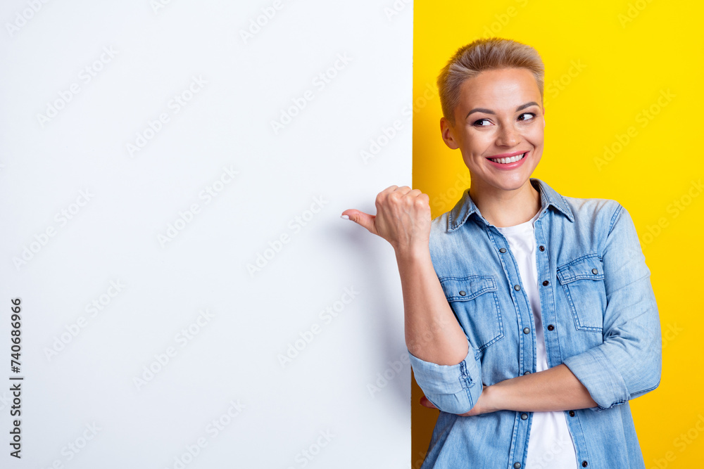 Photo portrait of lovely young lady point look empty space white wall dressed stylish denim garment isolated on yellow color background Photo portrait of lovely young lady point look empty space white wall dressed stylish denim garment isolated on yellow color background