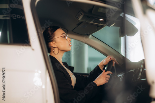 Happy woman customer female buyer client in shirt hold put hand on steering wheel choose auto want buy new automobile in car showroom vehicle salon dealership store motor show indoor. Sales concept