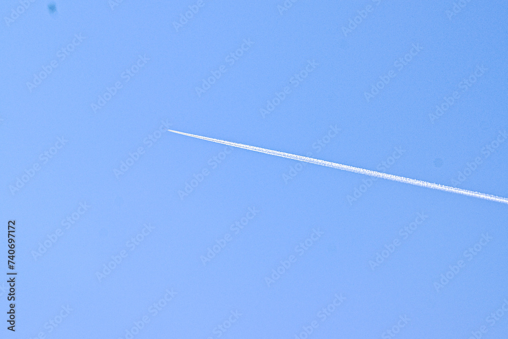 Thermal trace from a flying airplane in the middle of a clear cloudless blue sky Thermal trace from a flying airplane in the middle of a clear cloudless blue sky
