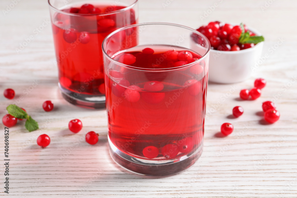 Tasty cranberry juice in glasses and fresh berries on white wooden table Tasty cranberry juice in glasses and fresh berries on white wooden table