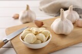 Fresh garlic and knife on white wooden table, closeup