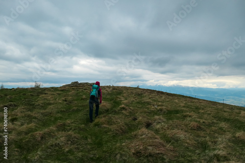 Hiker woman on dry alpine meadow with restricted view of hills and mountains in Mur Valley, Lavanttal Alps, Styria, Austria. Misty atmosphere in remote Austrian Alps. Dark clouds accumulating to storm photo