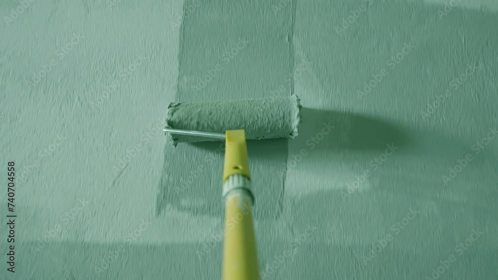 Painting Grey wall with paint roller . Close Up Shot of White Paint being applied on a wall. Room Renovations at Home concept. Painter man painting the wall in home. Camera attached to the brush