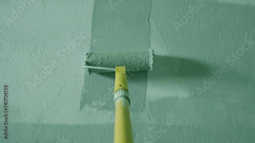 Painting Grey wall with paint roller . Close Up Shot of White Paint being applied on a wall. Room Renovations at Home concept. Painter man painting the wall in home. Camera attached to the brush