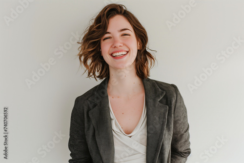 Cheerful Young Businesswoman in Stylish Blazer Enjoying a Successful Moment on Plain Background