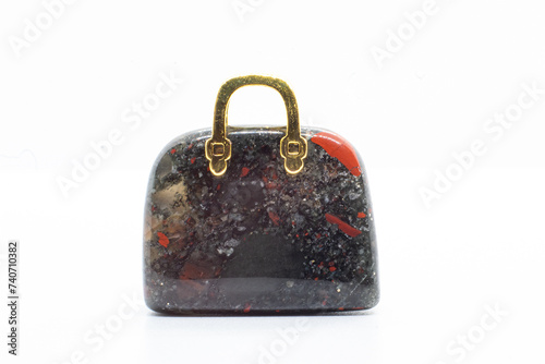 Blood stone Chalcedony, Heliotrope opaque silicate mineral, Crystal carving Bag with a gold metal handle isolated on white background surface  photo