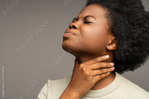African american woman suffering from sore throat, swallowing discomfort, voice loss. Sick female touching neck with painful face expression caused by respiratory infection, laryngitis, tonsillitis photo