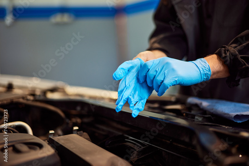 A close-up of the mechanic putting on protective gloves, ready for a car check.