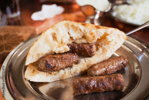 Bosnian Cevapi – the National Dish of Bosnia and Herzegovina made with minced beef and lamb and i served with onions, ajvar and somun bread photo