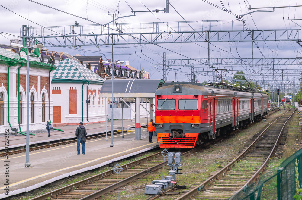 Electric transport on the railway. Contact power lines for commuter trains. People get on an electric train on the platform. Railway tracks at the railway station.Transportation of passengers by train