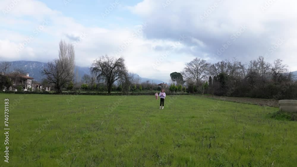 Tracking shot of wo little girls running towards camera in green fields Tracking shot of wo little girls running towards camera in green fields