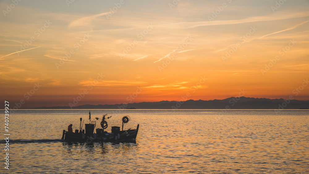 Fishing boat sailing at sunset
