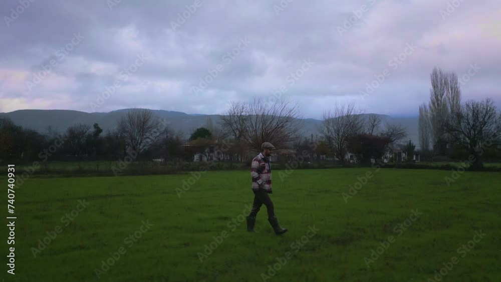 Tracking shot of a man, farmer walking in the green fields Tracking shot of a man, farmer walking in the green fields