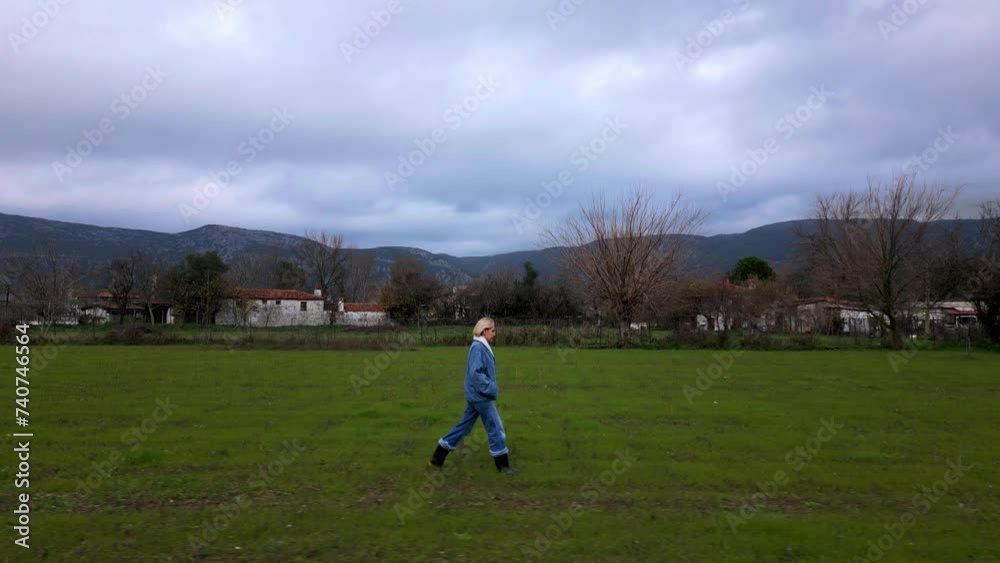 Tracking shot of a woman walking in the green fields
