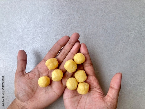 Hand holding Crispy corrugated potato chips or potato chips and Cheese Corn balls. Junk food. Close up. Keripik Singkong or Keripik Kentang dan snack bulat photo