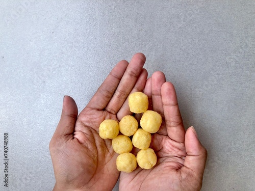 Hand holding Crispy corrugated potato chips or potato chips and Cheese Corn balls. Junk food. Close up. Keripik Singkong or Keripik Kentang dan snack bulat photo