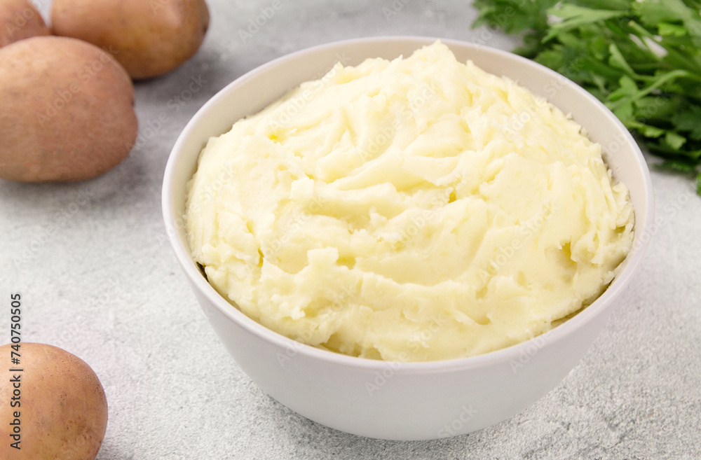Bowl of tasty mashed potato, parsley, and pepper on grey marble table Bowl of tasty mashed potato, parsley, and pepper on grey marble table