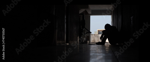 Depression.Desperate man in silhouette sitting on walkway of residence building. psychological problem, sadness, Cry, drama, lonely and unhappy. Negative emotion and mental health concept. copy space.