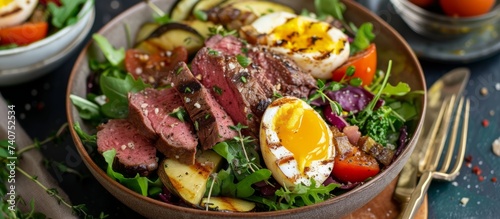 Delicious steak salad with poached egg, ripe tomato, and fresh arugula leaves