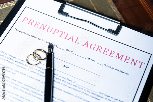 Close-up of a prenuptial agreement form with wedding rings and a fountain pen, indicating the legal aspects of marriage preparation. photo