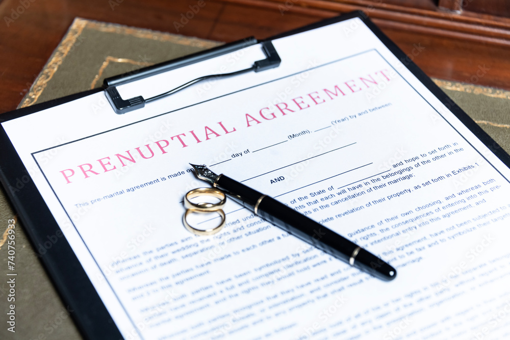 Close-up of a prenuptial agreement form with wedding rings and a fountain pen, indicating the legal aspects of marriage preparation. Close-up of a prenuptial agreement form with wedding rings and a fountain pen, indicating the legal aspects of marriage preparation.
