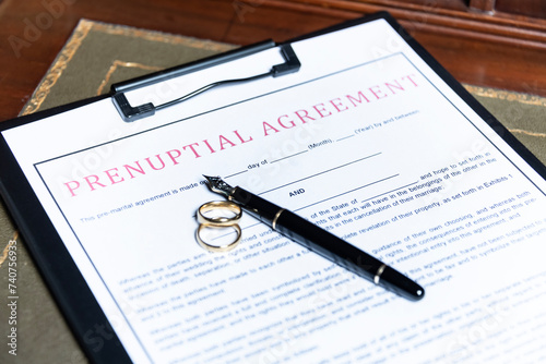 Close-up of a prenuptial agreement form with wedding rings and a fountain pen, indicating the legal aspects of marriage preparation.