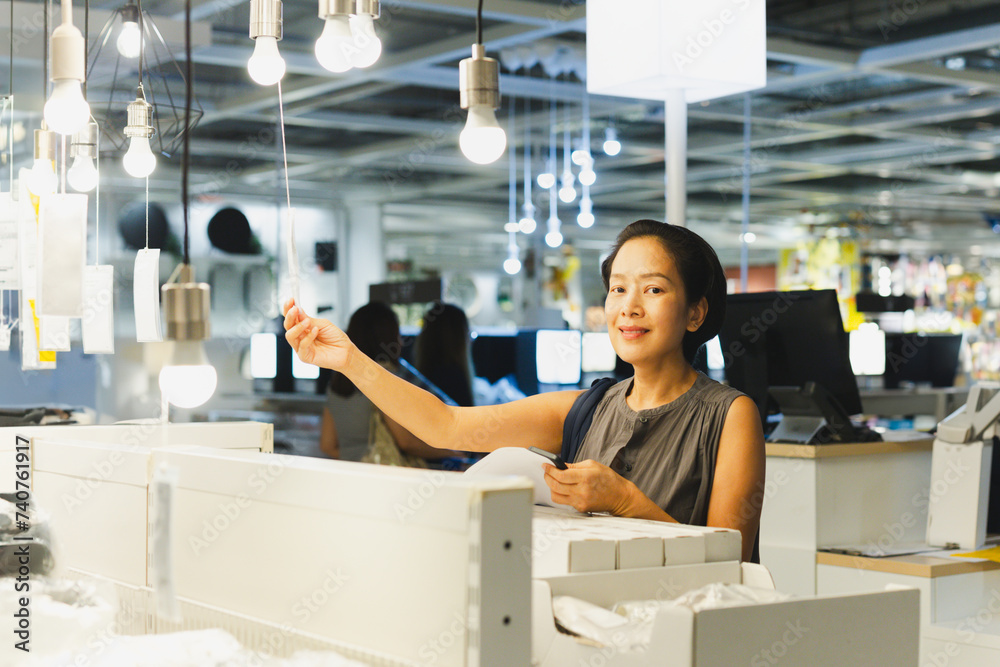 Naklejka premium Energy efficient lighting choice: Woman holding and choosing a LED light bulb.