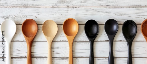 Collection of rustic wooden spoons on a clean white wooden background for kitchen utensil concept