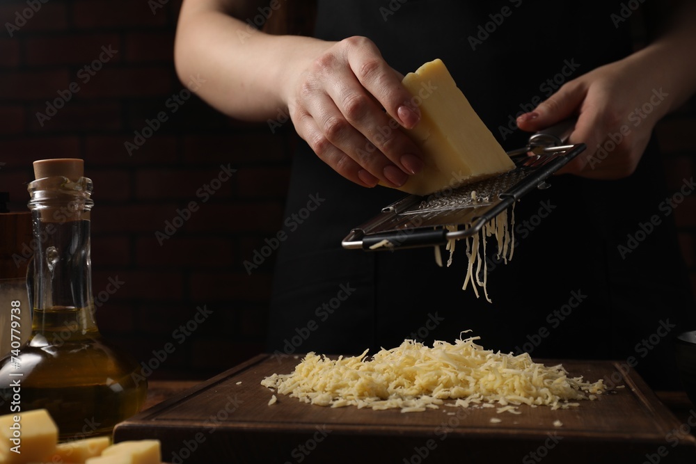 Woman grating cheese at wooden table, closeup - obrazy, fototapety, plakaty 