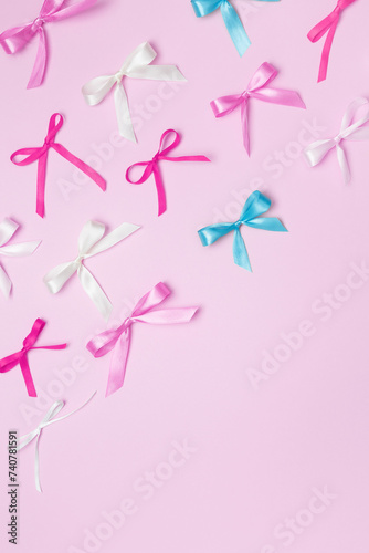 Multicolored bows on pink background. Top view, copy space