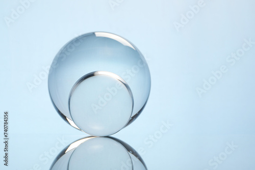 Transparent glass balls on mirror surface against light background. Space for text