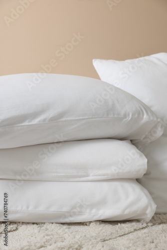 Soft white pillows near beige wall indoors