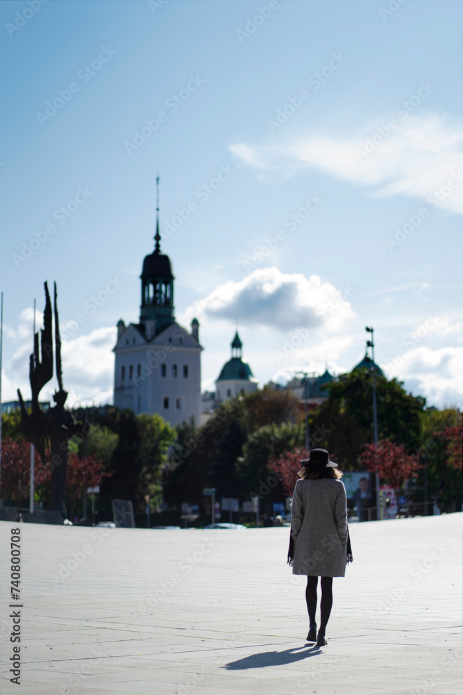 A girl walks along the city square towards the ancient castle