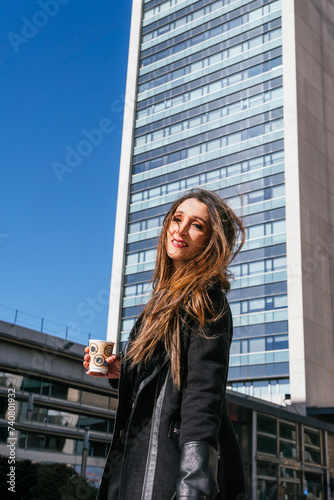 Business woman drinking coffee outside business center looking at camera © Miguel Paricio