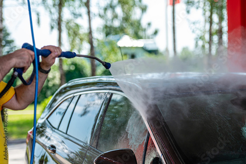 Closeup car washing with high pressure car washer spray gun