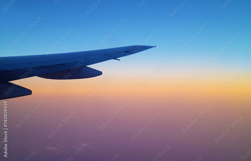 Stunning sunrise sky with airplane wing seen from plane window during flight