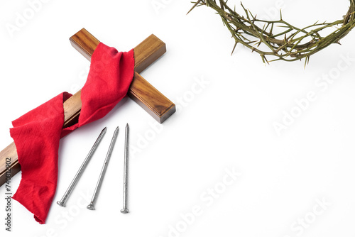 Jesus Wooden cross wrapped with red cloth next to nails and Crown of Thorns used by Catholic Christians on Good Friday Ceremony. Isolated on white background with empty blank copy text space. photo