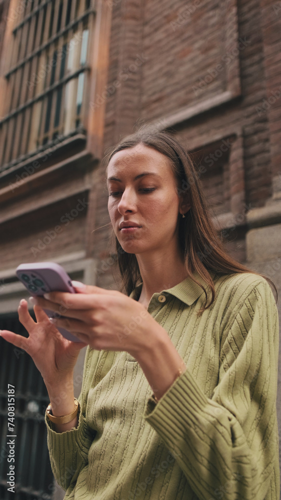 Close-up of a young woman using a mobile phone on the street of a European city Close-up of a young woman using a mobile phone on the street of a European city