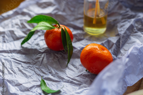 Mandarins  on purple craft paper with a bottle of aromatic essential oil.  Ripe clementines or  tangerines. Orange  essential oil.
