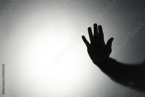 Silhouette of ghost behind glass against light background, closeup. Space for text