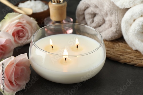 Spa composition with burning candle and rose flowers on grey table  closeup
