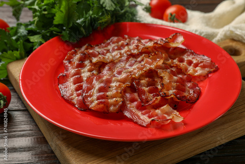 Plate with fried bacon slices, tomatoes and parsley on wooden table, closeup © New Africa