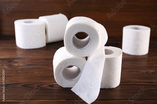 Many soft toilet paper rolls on wooden table, closeup