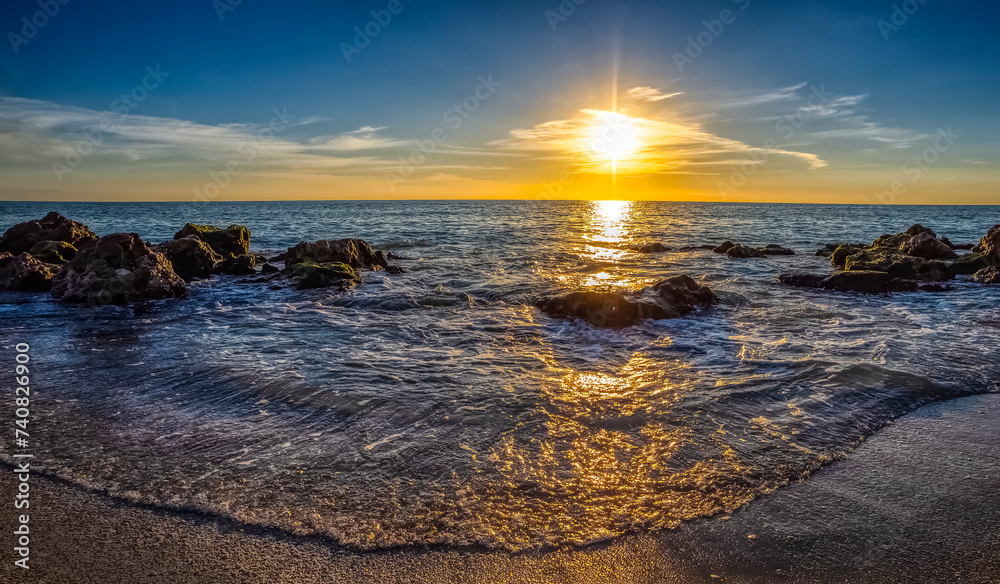 Small waves washing up on rocky beach of the Gulf of Mexico at Caspersen Beach at sunset in Venice Florida USA